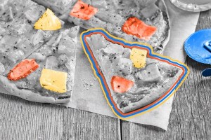 A slice of Hawaiian pizza cut out of a pie