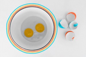 Two eggs cracked into a bowl with their shells nearby