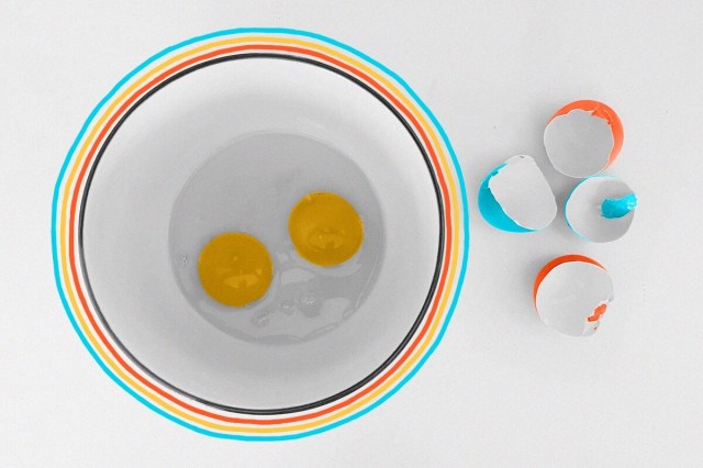 Two eggs cracked into a bowl with their shells nearby