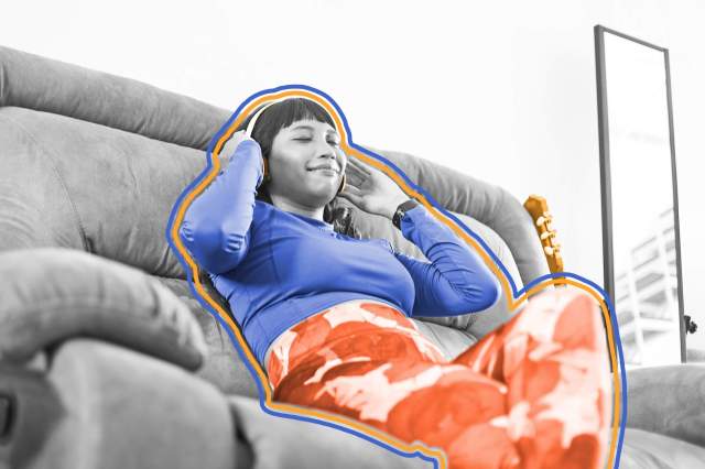 Woman wearing headphones , sitting on a couch, and humming to music