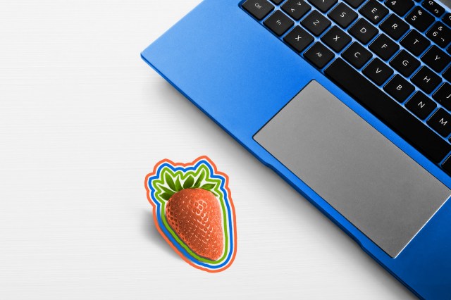 Open laptop on table with a strawberry