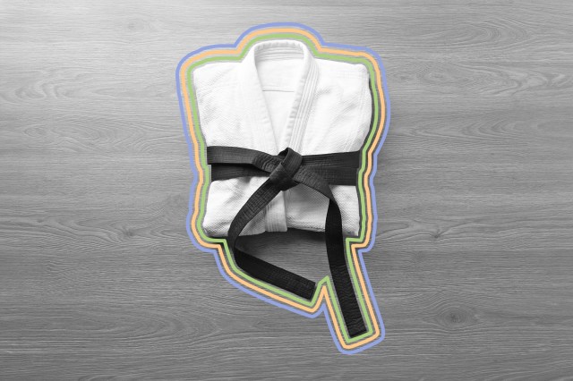 Martial arts uniform with black belt on wooden background