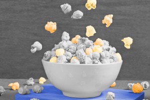 Bowl of popcorn with pieces flying around it