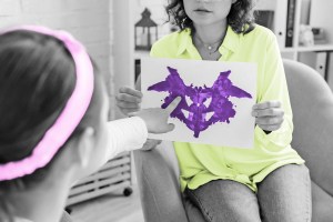 Girl pointing to an image of a Rorschach test inkblot held by a woman