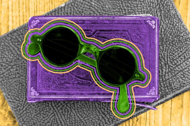 Top view of old round glasses laying atop a stack of books