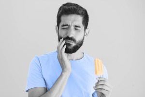 Man wincing in pain while eating popsicle