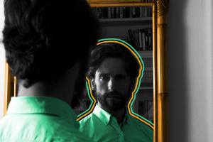 Man staring at his reflection in a dimly lit mirror