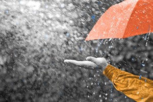 Person holding out their hand under an umbrella in the rain