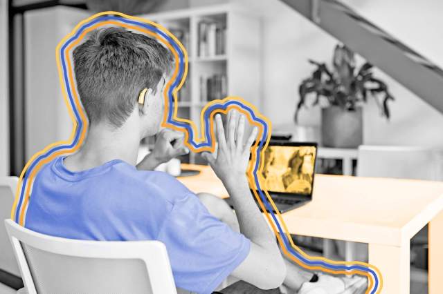 Over-the-shoulder view of teenage boy signing with his parents over video chat