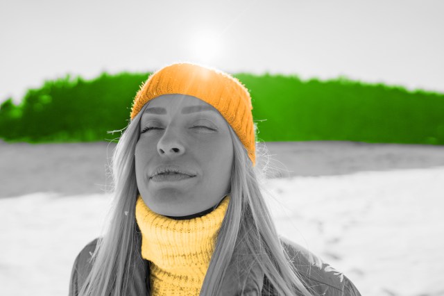 Woman closing her eyes and inhaling in wintry landscape