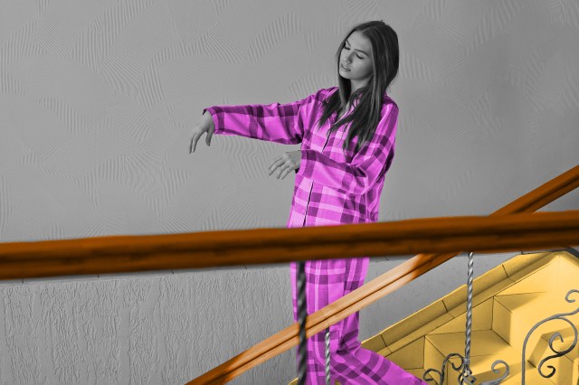 Woman in pajamas sleepwalking down the stairs