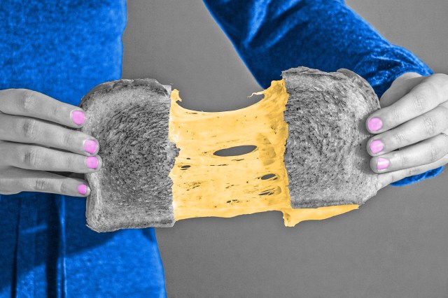 Hands pulling grilled cheese apart with cheese stretching in the middle